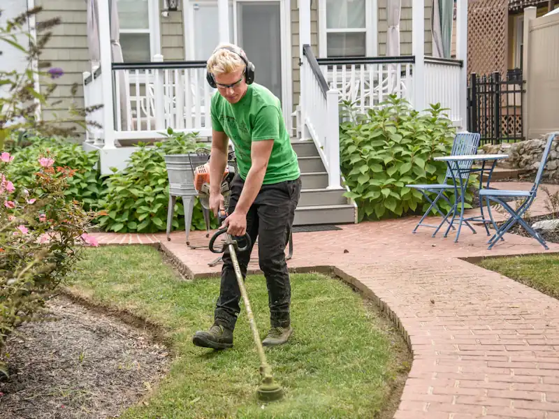 Membre de l'équipe Bellerive au travail, taille des bordures le long d'un sentier